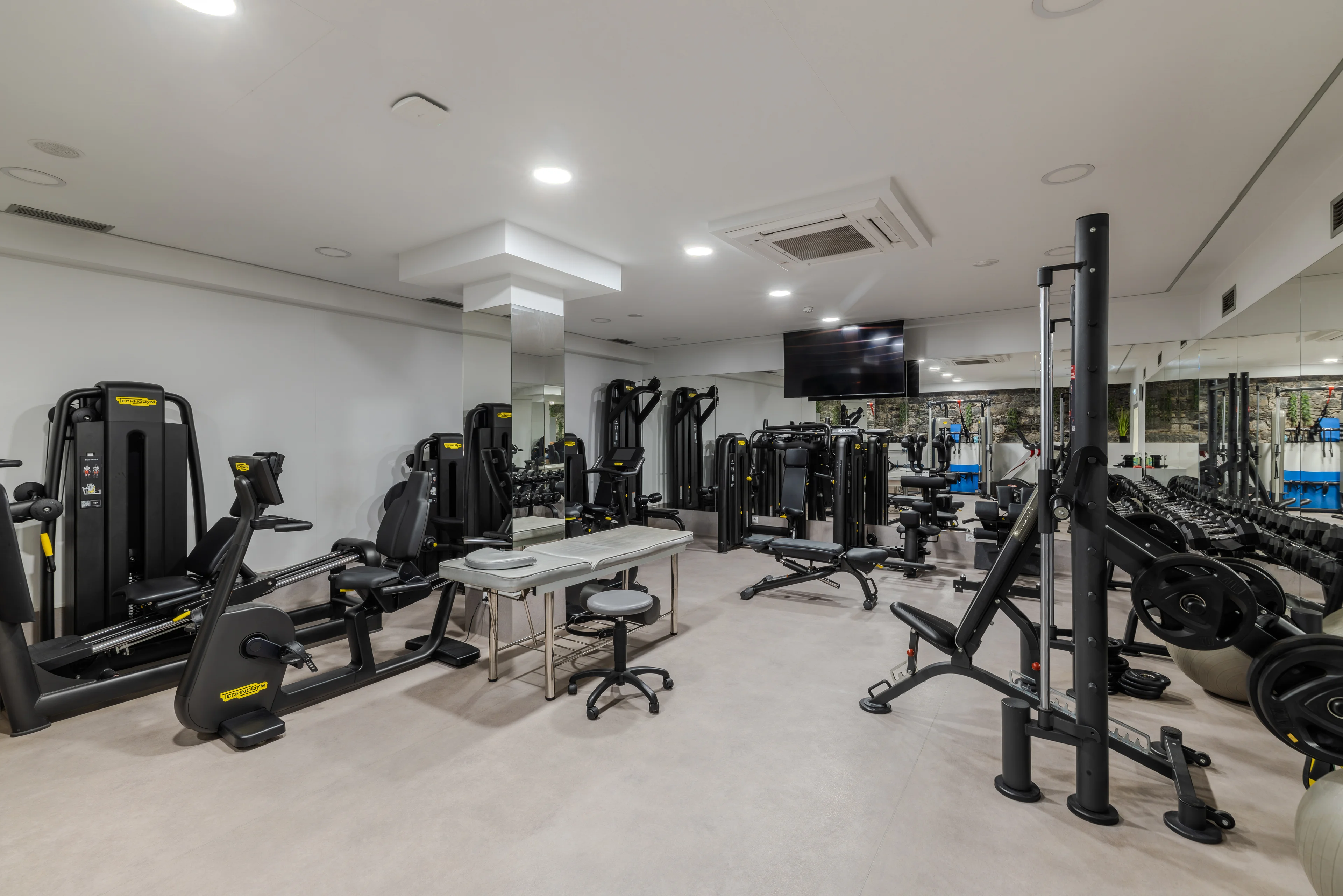 Interior do ginásio da Mais Clinic com equipamentos de exercício e área de reabilitação.
